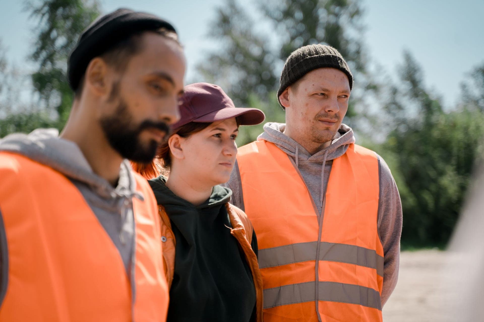 Three workers in orange high-visibility vests standing outside