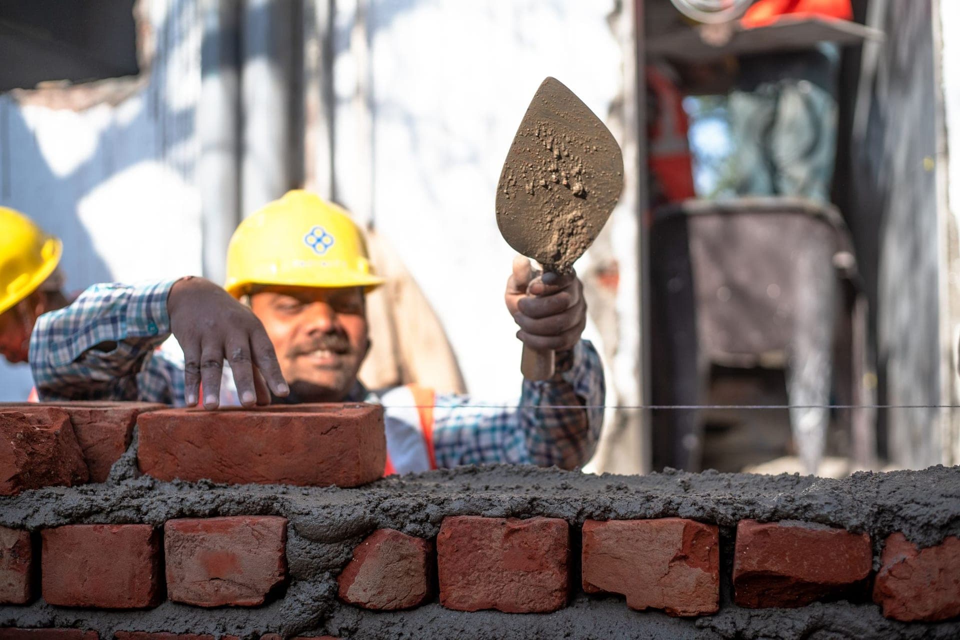 Bricklayer setting a brick into fresh mortar with a trowel