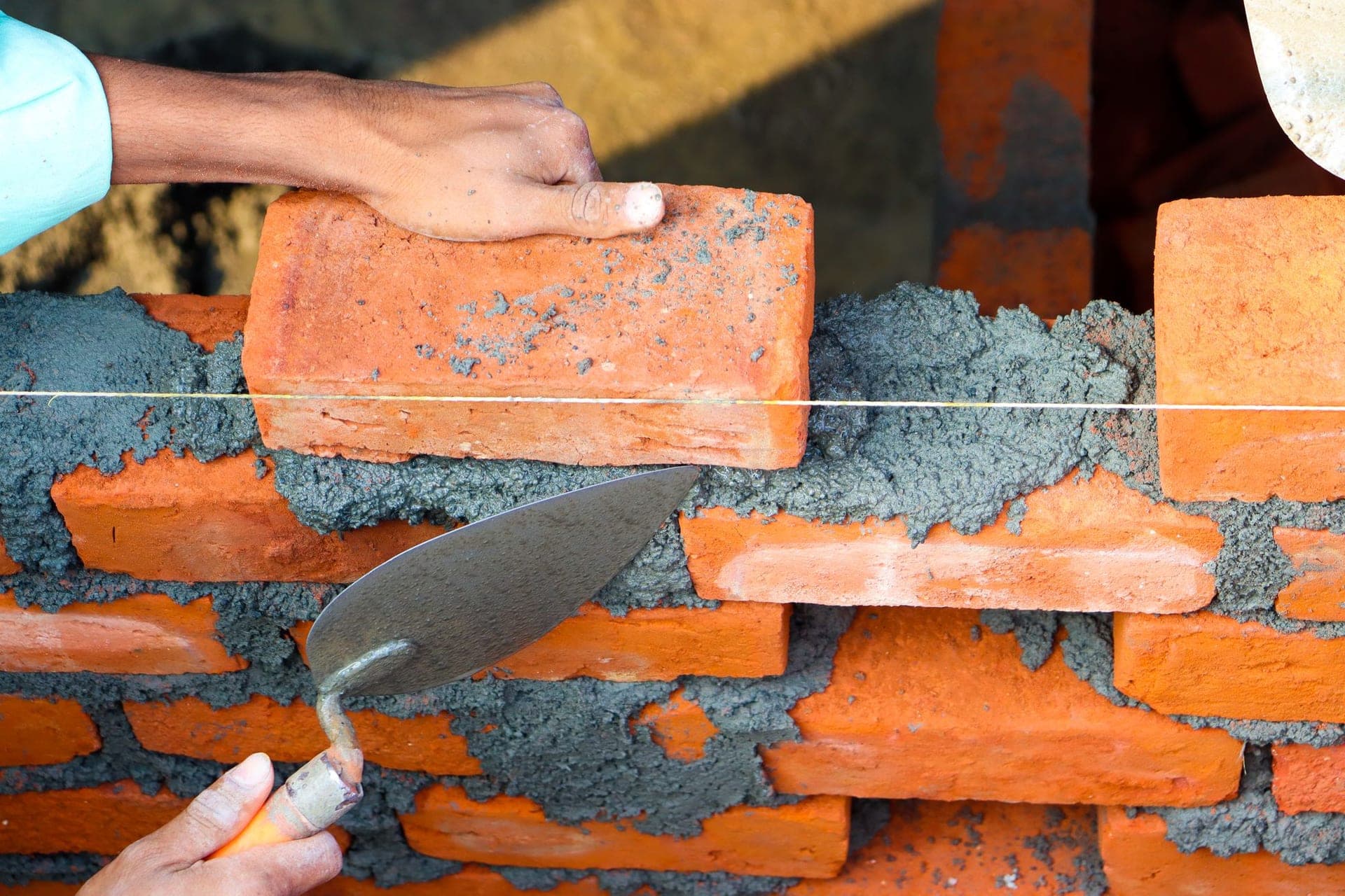 Mason setting a brick into fresh mortar with a trowel